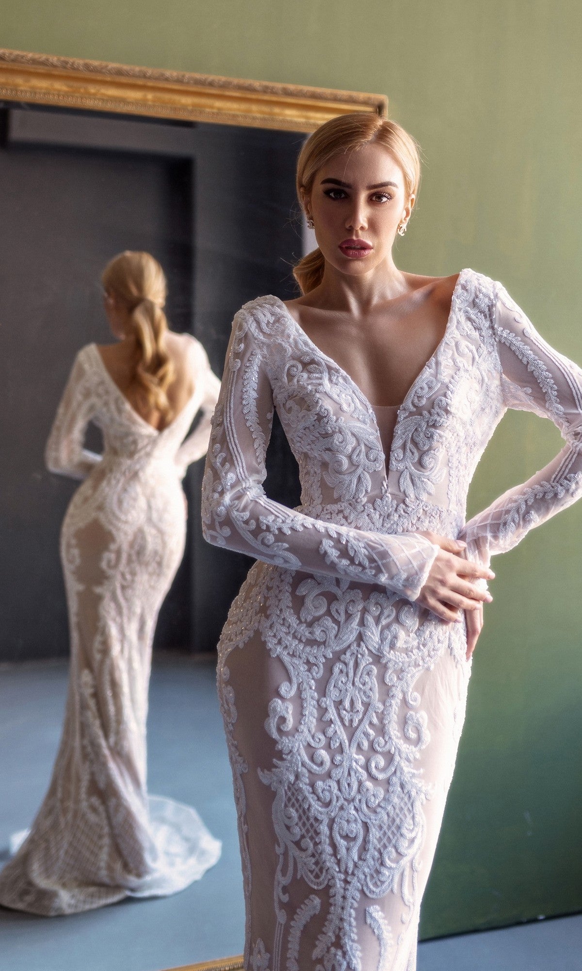 A woman models the Tina Holly BB021 Long Sleeve White Bridal Gown in front of a mirror, displaying both the front and back views.